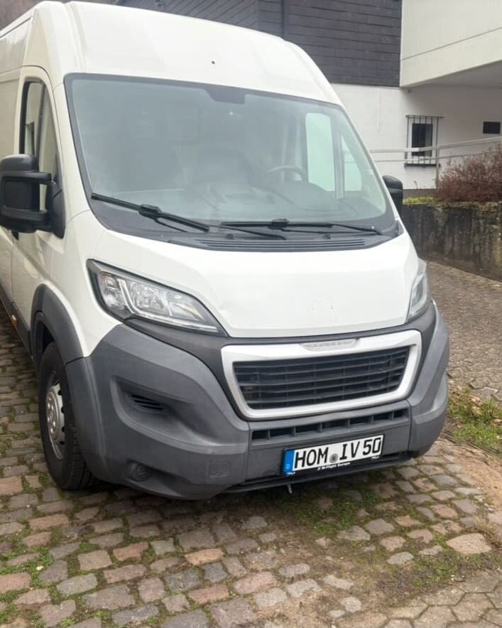 Weißer Transporter von Intercity Verleih auf Kopfsteinpflaster vor einem Wohnhaus